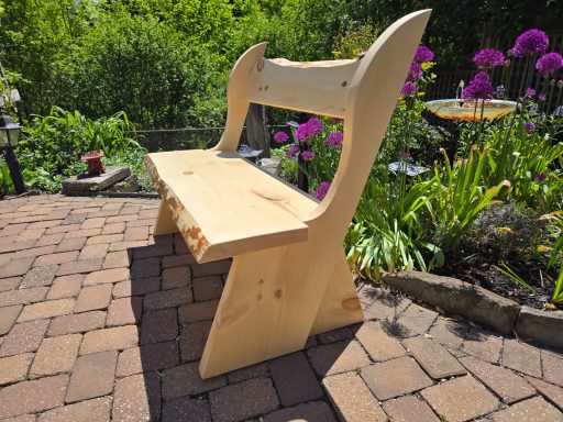 Wooden bench in a garden surrounded by blooming flowers and greenery.
