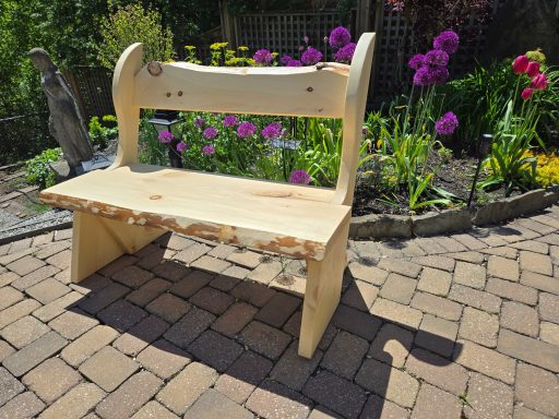Wooden garden bench beside vibrant flowers in a landscaped area.