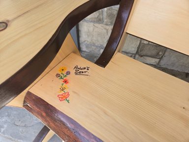 Wooden chair with decorative floral artwork on the seat.
