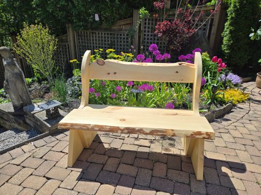 A rustic wooden bench in a garden surrounded by colorful flowers.